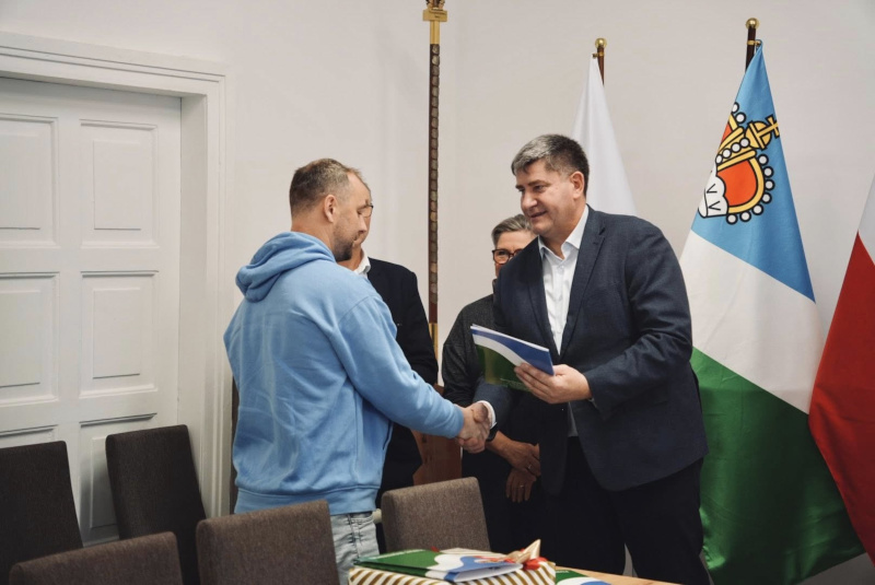Starosta Piotr Rusiecki gratuluje i wręcza nagrodę wyr&oacute;żnionemu sportowcy